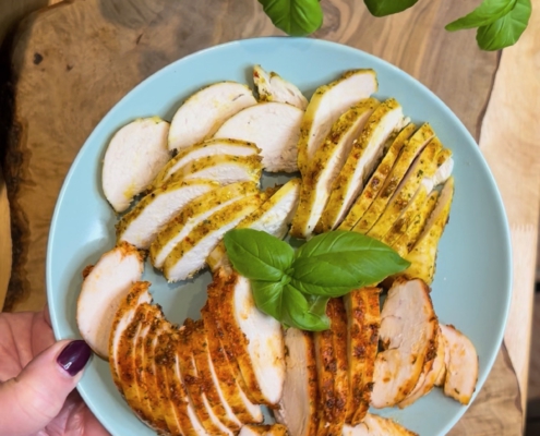 Zwei marinierte Hähnchenbrustfilets (Curry und Paprika) aufgeschnitten in dünne, saftige Scheiben auf einem Teller