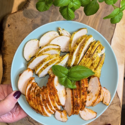 Zwei marinierte Hähnchenbrustfilets (Curry und Paprika) aufgeschnitten in dünne, saftige Scheiben auf einem Teller