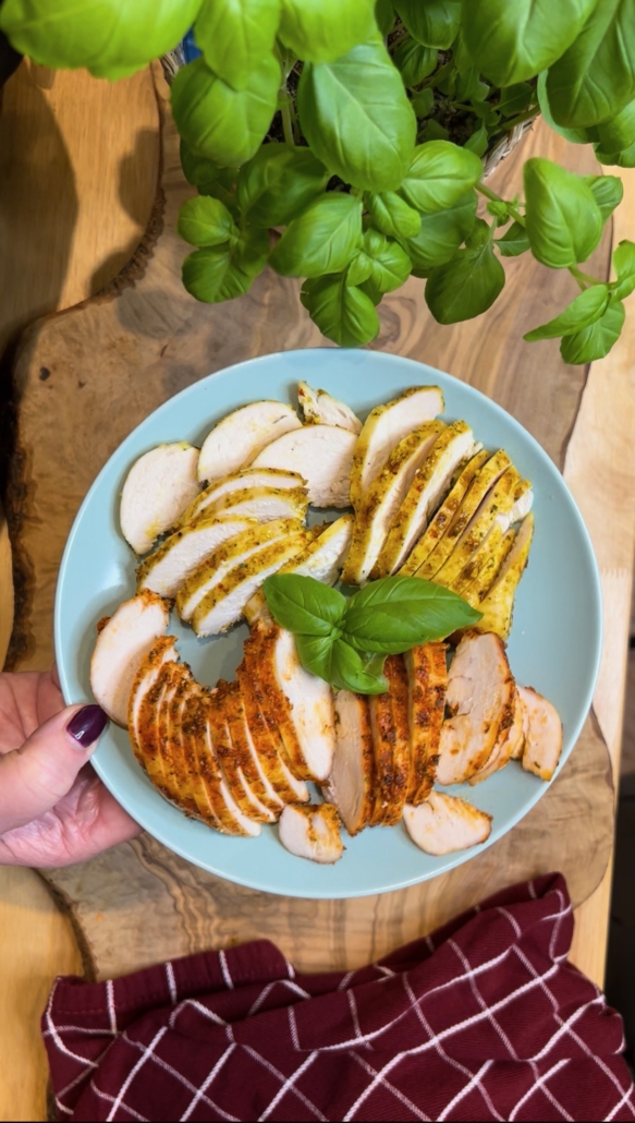 Zwei marinierte Hähnchenbrustfilets (Curry und Paprika) aufgeschnitten in dünne, saftige Scheiben auf einem Teller