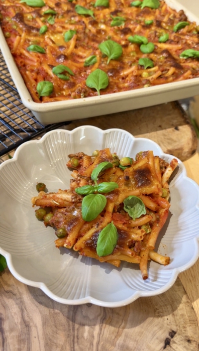 Deftiger Macaroni-Auflauf mit Hackfleisch, Erbsen und geschmolzenem Mozzarella auf dem Großen Ofenzauberer, serviert mit frischem Basilikum.