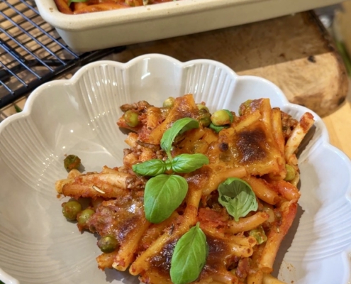 Deftiger Macaroni-Auflauf mit Hackfleisch, Erbsen und geschmolzenem Mozzarella auf dem Großen Ofenzauberer, serviert mit frischem Basilikum.